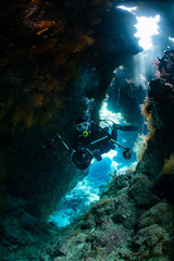 typical underwater cave in a red sea reef with an underwater photographer diver