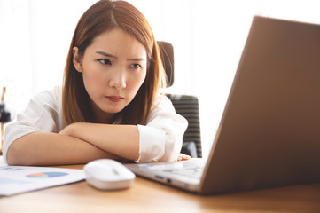 Stressed young Asian woman using laptop working at home