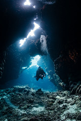 typical underwater cave in a red sea reef with an underwater photographer diver