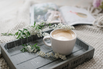 A cup of coffee on the wooden tray and knitting plaid