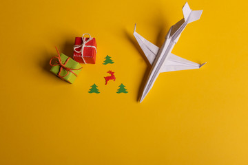 Group of paper plane in one direction and with one individual pointing in the different way on yellow background. Christmas ttrip. Presents and gifts.
