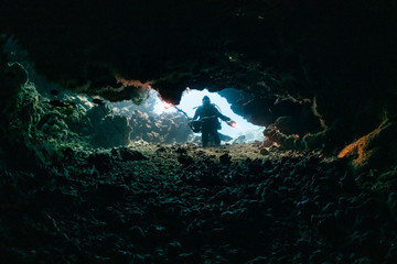 typical underwater cave in a red sea reef with an underwater photographer diver
