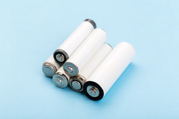 many new and used batteries of different shapes, AA, round batteries on a blue background.