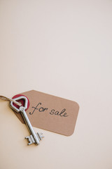 Top view of key with trinket with for sale lettering on white background
