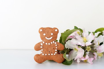 Cute gingerbread bear surrounded by tender blooming twig - greeting card for birthday or baby birth, copy space for text
