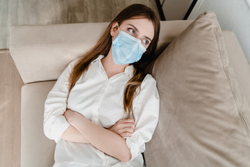 woman at home on couch wearing mask taking her on and off