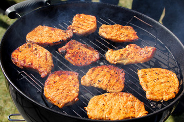 beautiful grilled roasted meat steaks grilled on the street on a black metal grill on burning coals, picnic concept, close-up