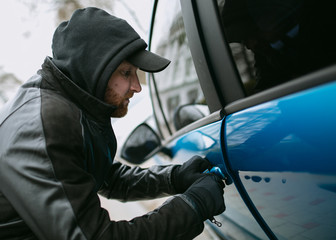 Car thief stealing a car at the car door,
glove robber breaks the law, hacks the lock on the car to get inside