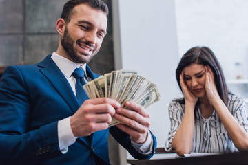 Low angle view of happy collector with money near stressed woman in room - obrazy, fototapety, plakaty
