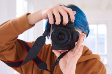 hipster girl holding camera and taking photo. closeup of hand of young woman with professional camera in photo studio. world photography day concept