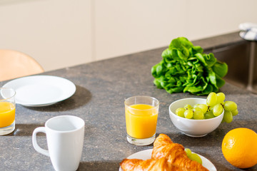 Breakfast with oranges, fruits, croissants, cake and coffee, magazine decorated table 