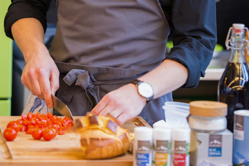 Man Cutting  Cherry Tomatoes and Preparing a Meal on Wooden Chopping Board