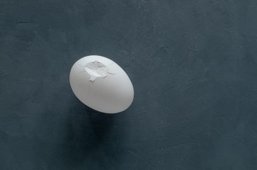 White broken chicken egg with cracks on a black background. Horizontal orientation. 