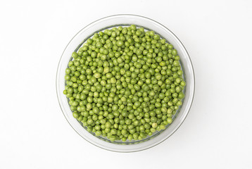 Fresh green peas in a glass bowl isolated on white background. top view