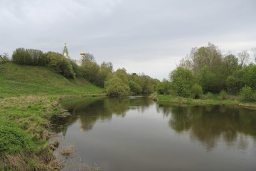 Spring landscape with river, gray sky and small church domes
