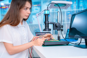 Young woman in inspection electronics PCB devise. Modern electronics laboratory