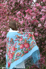 Russian fashionable girl in vintage Pavlovo Posad shawl. Pink flowers of blossoming apple-tree,...