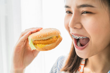Happy young Asian woman holding burger for eat.