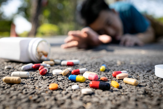 Sick asian man have any chronic health conditions,heart attack lying on the floor after falling down,male people trying to reach for a bottle of medicine,lot of pills at the street,medical emergency
