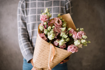 Very nice young woman holding beautiful blossoming mono bouquet of fresh eustoma flowers in tender...