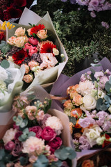 Beautiful blossoming colourful flower bouquets of roses, carnations, eustoma, eucalyptus, mathtiola, gerbera, chrysanthemum, at the florist shop, top view, flat lay, vertical photo