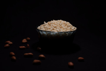 A bowl of puffed rice decorated with peanuts in a dark copy space background. Food and product photography.
