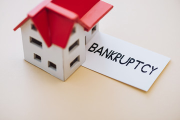 High angle view of card with bankruptcy lettering and house model on white