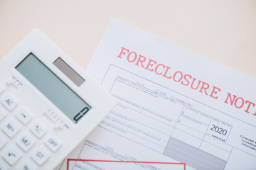 Top view of document with foreclosure lettering and calculator on white background