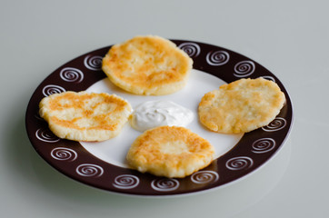 Cheese pancakes or syrniki (cheesecakes, curd fritters) with sour cream or smetana for breakfast