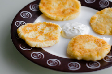 Cheese pancakes or syrniki (cheesecakes, curd fritters) with sour cream or smetana for breakfast