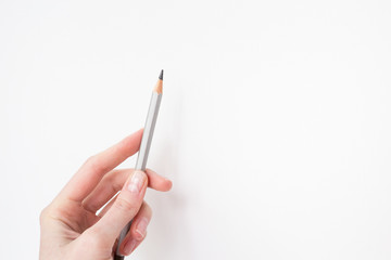 One gray pensil on the hand in the white canvas background. Drawing by pencils. Hobby during quarantine. Inspiration, talent. Creating a new picture, sketch. An artist. Art.