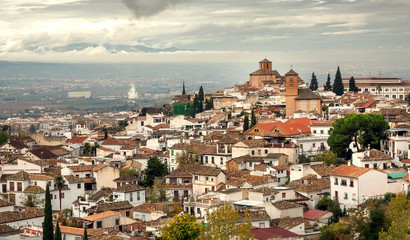 Fototapeta na wymiar Cityscape with old houses of Granada under rainy clouds. Landscape of historical town of Andalusia, Spain.