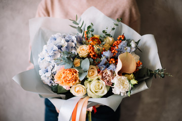 Very nice young woman holding big beautiful blossoming bouquet of fresh hydrangea, roses,...
