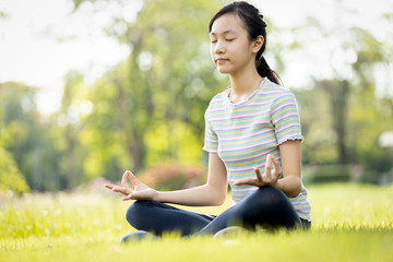 Happy woman meditating on the grass at park,asian child girl practicing yoga meditation in nature...