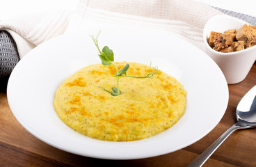 Mixed vegetable cream soup in a white bowl, isolated on a white background, on wooden cutting board