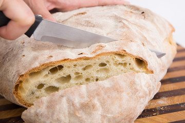 Closeup of cutting of freshly baked homemade round bread in slices. Isolated object on white background. Healthy food for breakfast concept