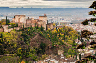 Fototapeta na wymiar Alhambra castle on green hill at autumn. Old structures of Granada . View of historical town of Andalusia, Spain.