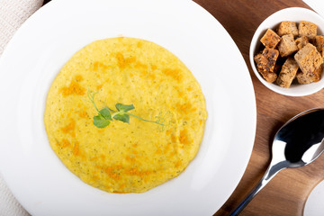 Mixed vegetable cream soup in a white bowl, isolated on a white background, on wooden cutting board