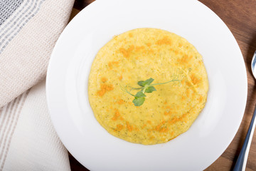 Mixed vegetable cream soup in a white bowl, isolated on a white background, on wooden cutting board
