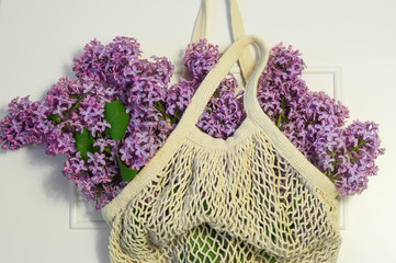 Blooming spring lilac flowers in string bag. Spring background