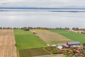Naklejka premium View of Lake Vattern with a picturesque little Swedish village and the plowed field on the coast photographed from the fortress Brahehus in Granna, Jonkoping, Sweden.