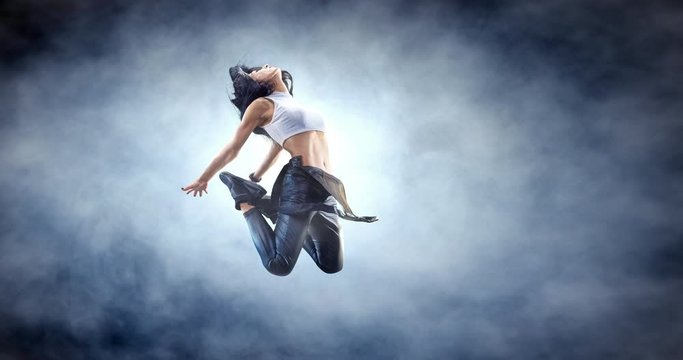 Female street dancer in a jump with fog on a backgroung.