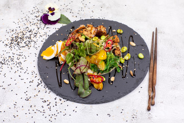 Poke bowl with chicken and vegetables on the white table.