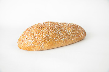 Baked at home wheat bread with cereal grains laying at table. Fresh loaf isolated on white background. Studio shot. Side view. Homemade food and baking at home concept