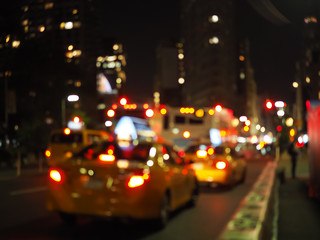 Defocus blur of New York City street scene at night with yellow taxi cabs, cars, lights and...
