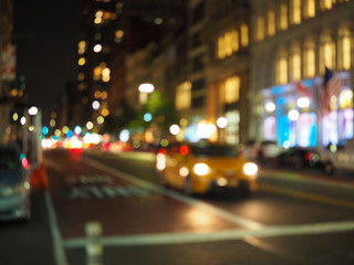 Fototapeta na wymiar Defocus blur of New York City street scene at night with yellow taxi cabs, cars, lights and buildings.