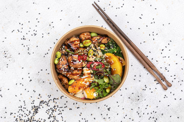 Poke bowl with chicken and vegetables on the white table.