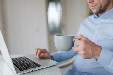 A man in blue shirt with notebook and cup of coffee