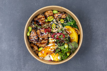 Poke bowl with chicken and vegetables on the white table.