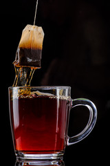 making tea from a tea bag in a transparent mug on a black background